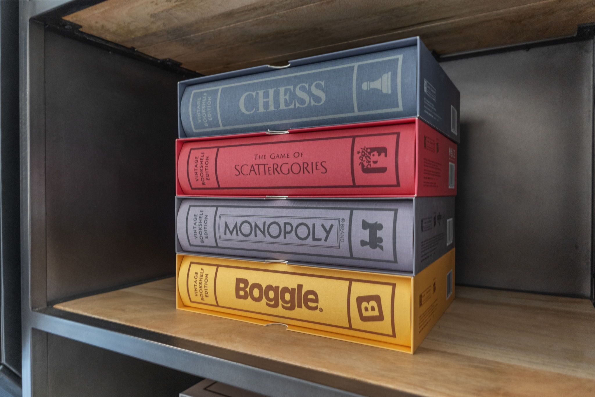 A shelf with four vintage board game boxes: Chess, The Game of Scattergories, Monopoly, and Boggle.