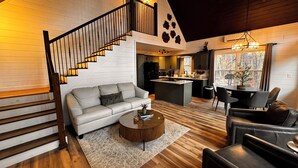 Un salon moderne avec un escalier, un coin repas et une cuisine.