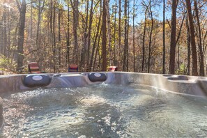 Een hottub in een bebost gebied, met bomen en een heldere lucht.