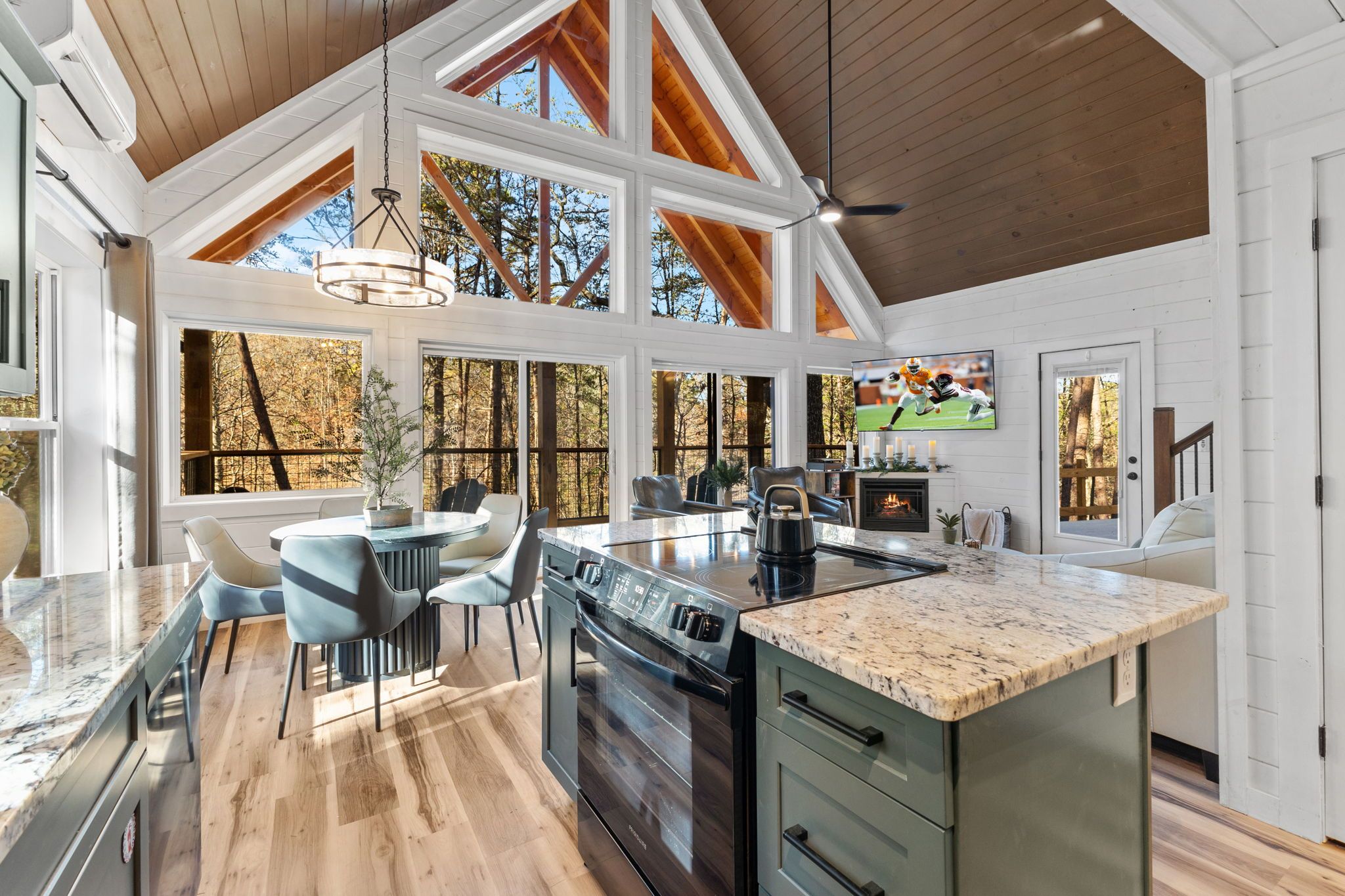 A spacious kitchen with a large island, wooden beams, and large windows.