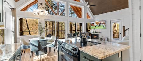 A spacious kitchen with a large island, wooden beams, and large windows.