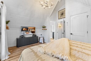 Une chambre à coucher avec un lit, une télévision, une cheminée et une porte.