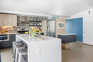 Una cocina moderna con una isla central, electrodomésticos de acero inoxidable y una pared de acento azul.