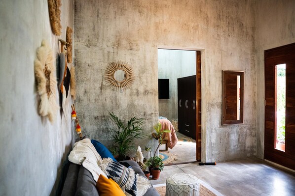 A cozy living room with a sofa, potted plants, and a rustic decor.