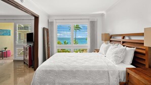 Una camera da letto con un letto grande, una testiera in legno, un comodino e una finestra vista oceano.