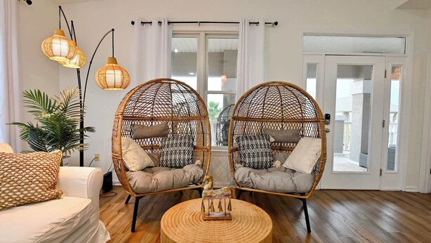 Una sala de estar con dos sillones de mimbre, una mesa redonda de madera y un sofá blanco.