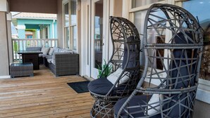 Un espacio al aire libre techado con sillas de mimbre, una mesa y un sofá.