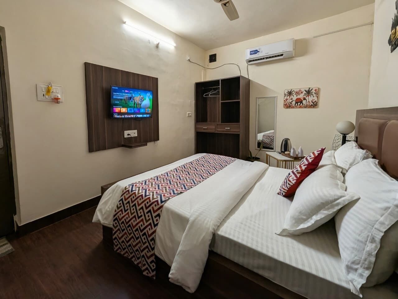 Ein Hotelzimmer mit einem Bett, einem Fernseher, einem Kleiderschrank und einem kleinen Tisch mit einem Wasserkocher.
