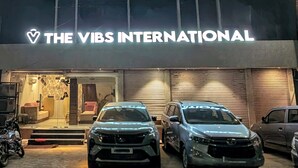 A building with a sign reading "THE VIBS INTERNATIONAL" and two cars parked in front. - The Vibs International (Damoh)