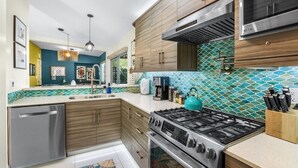 Une cuisine moderne avec des meubles en bois, une cuisinière en acier inoxydable et un dosseret carrelé.
