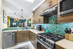 Uma cozinha moderna com armários de madeira, fogão de aço inoxidável e painel de azulejos.