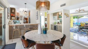 Une cuisine moderne avec une table ronde en marbre, des tabourets de bar et des luminaires suspendus.