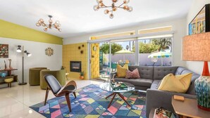 Un salon moderne avec un canapé, une table basse et des fauteuils, une cheminée et une grande fenêtre donnant sur un beau paysage.