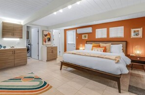 Une chambre à coucher comprenant un lit, des tables de chevet, une armoire et un lave-linge.