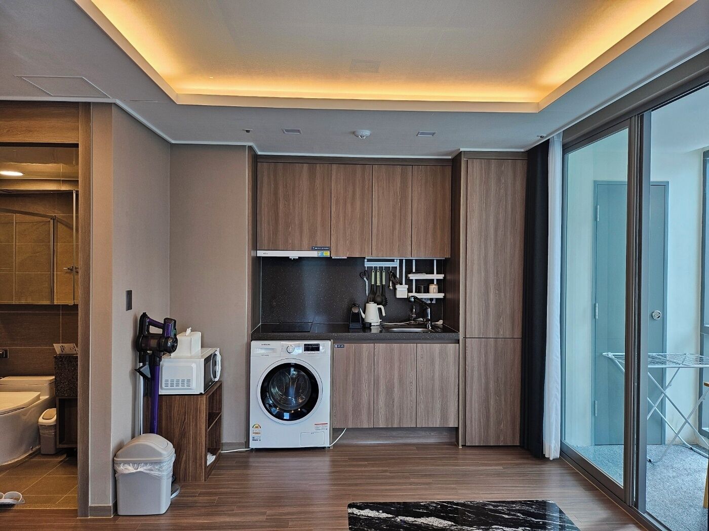 Una cucina moderna con lavatrice e asciugatrice integrate, mobili in legno e un'ampia finestra con vista.