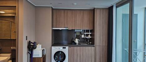 Una cucina moderna con lavatrice e asciugatrice integrate, mobili in legno e un'ampia finestra con vista.