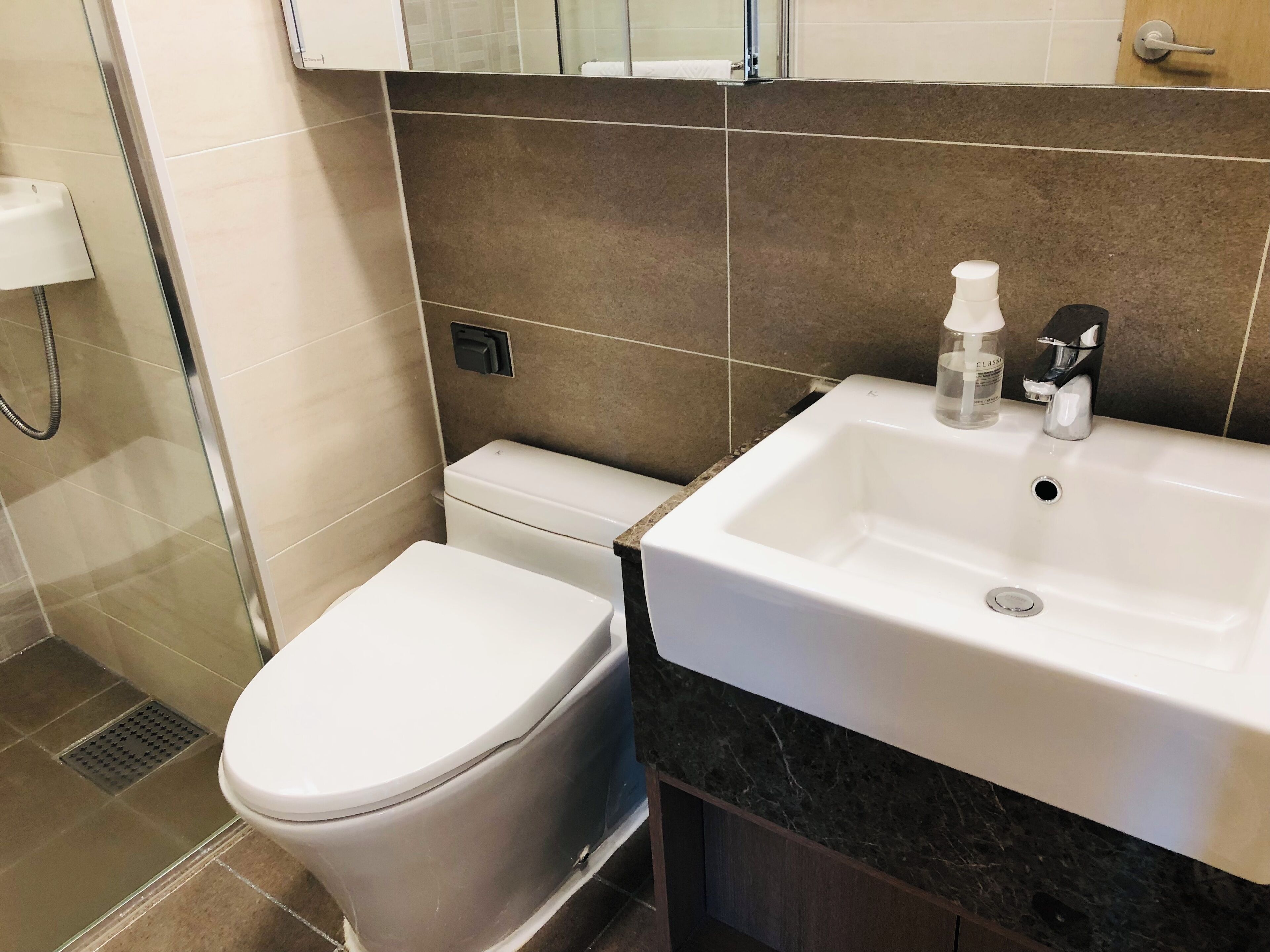 Une salle de bain avec des toilettes, un lavabo et une douche.