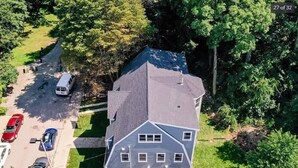 Une maison à deux étages avec un toit en pente, une allée et un espace de stationnement pouvant accueillir trois voitures.