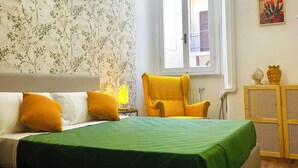 Une chambre à coucher comprenant un lit, une chaise, une fenêtre et un mur orné d’un motif floral.