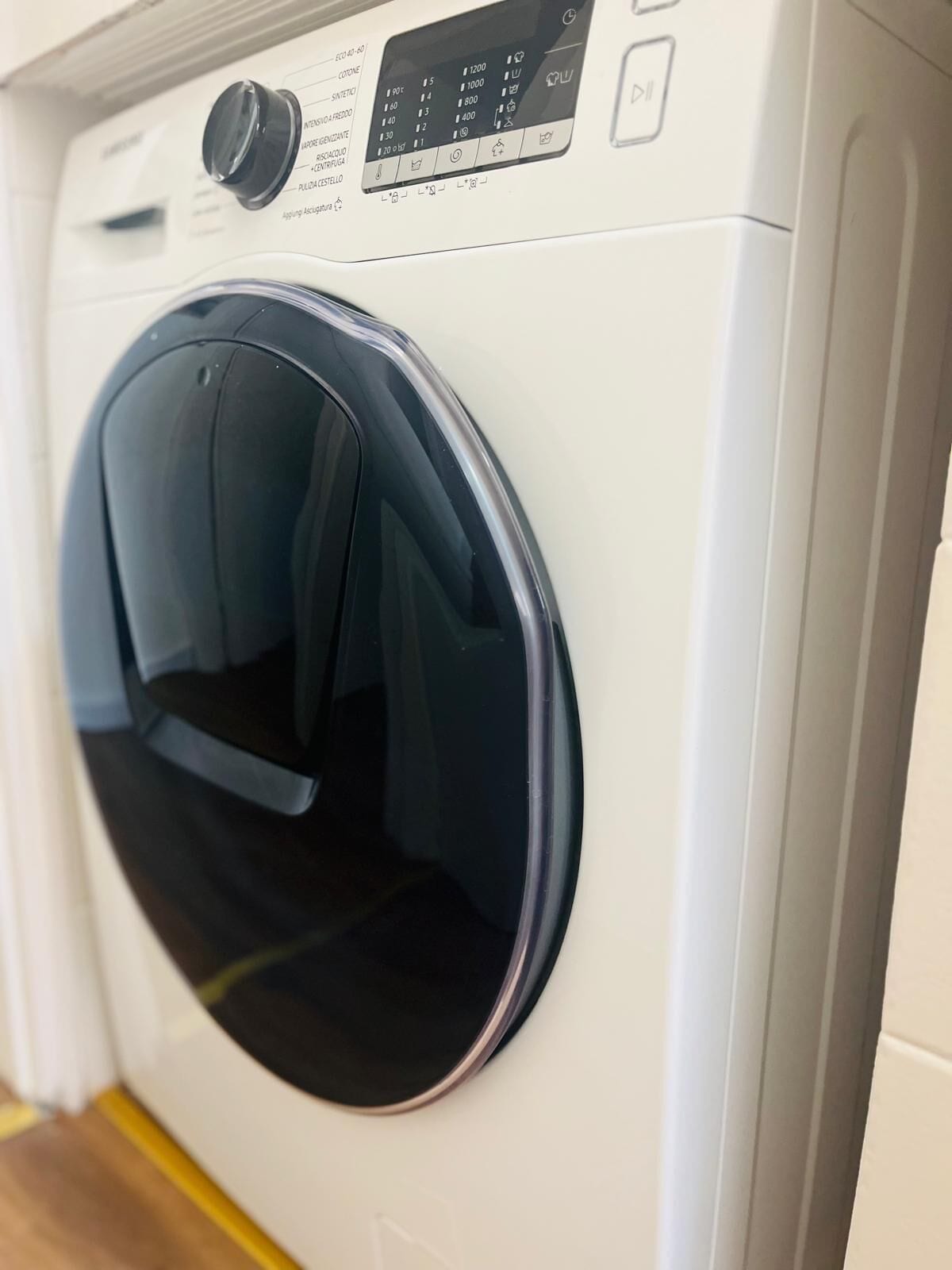 Vista frontal de una lavadora blanca con un panel de control que muestra varias configuraciones y botones.