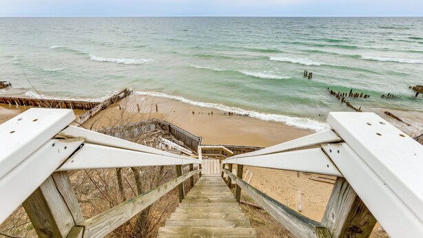Una escalera de madera que lleva a una playa con vistas al océano.