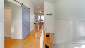 Un pasillo con piso de madera, paredes blancas y una puerta corredera azul.