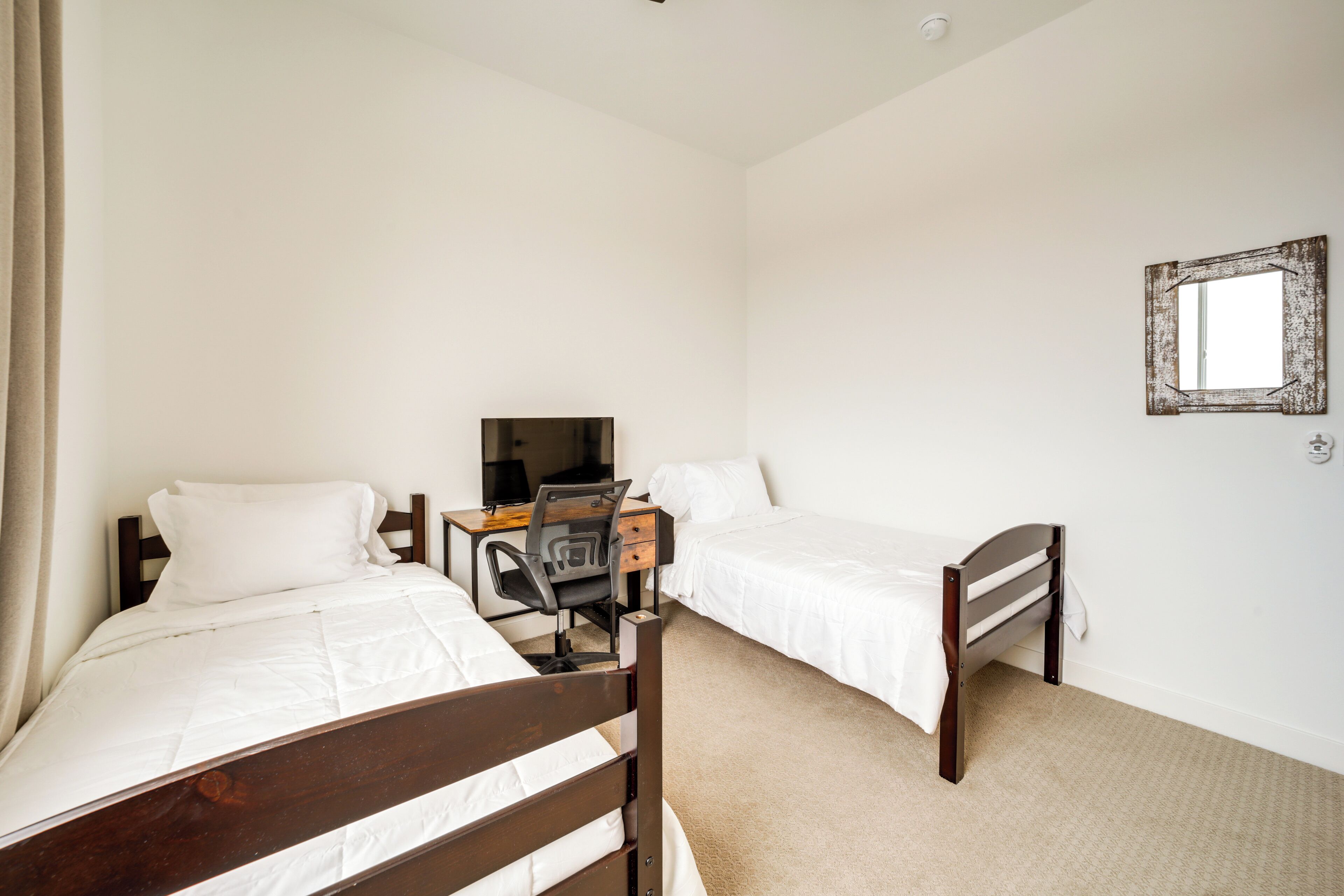 A bedroom with two single beds, a desk, and a chair.