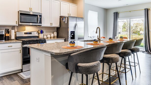 A modern kitchen with white cabinets, stainless steel appliances, and a bar area with grey barstools. - 5 Mi to Fort Harrison: Home w/ Pool Access! (McCordsville)