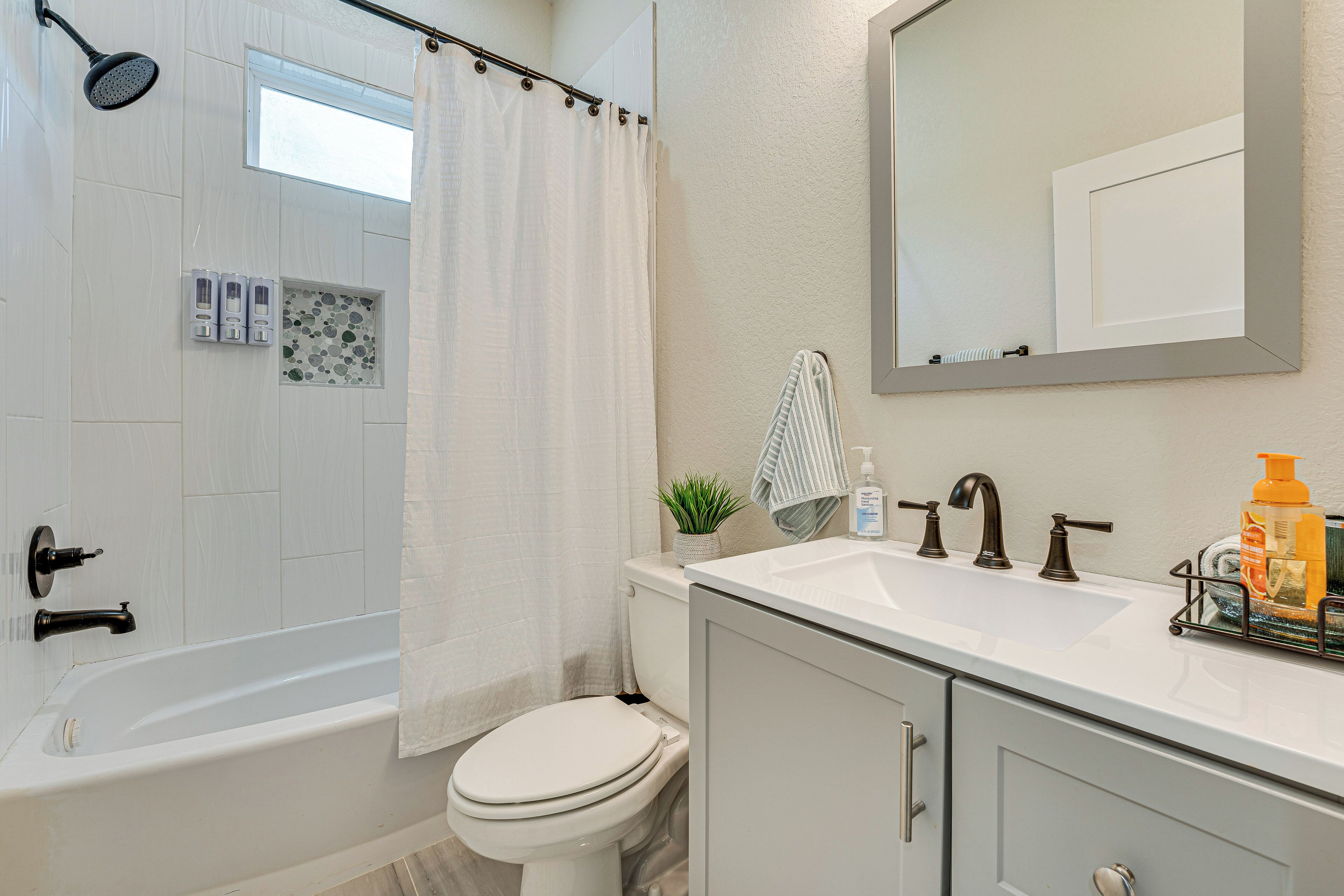 A bathroom with a bathtub, toilet, sink, and a mirror.