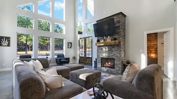 A spacious living room with a stone fireplace, large windows, and a comfortable seating area.