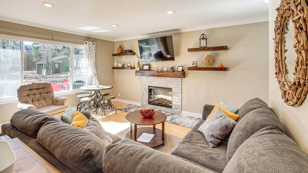 A cozy living room with a fireplace, comfortable seating, and a television mounted on the wall. - Walk to Giant Steps & Hot Tub: Brian Head Condo! (Brian Head)