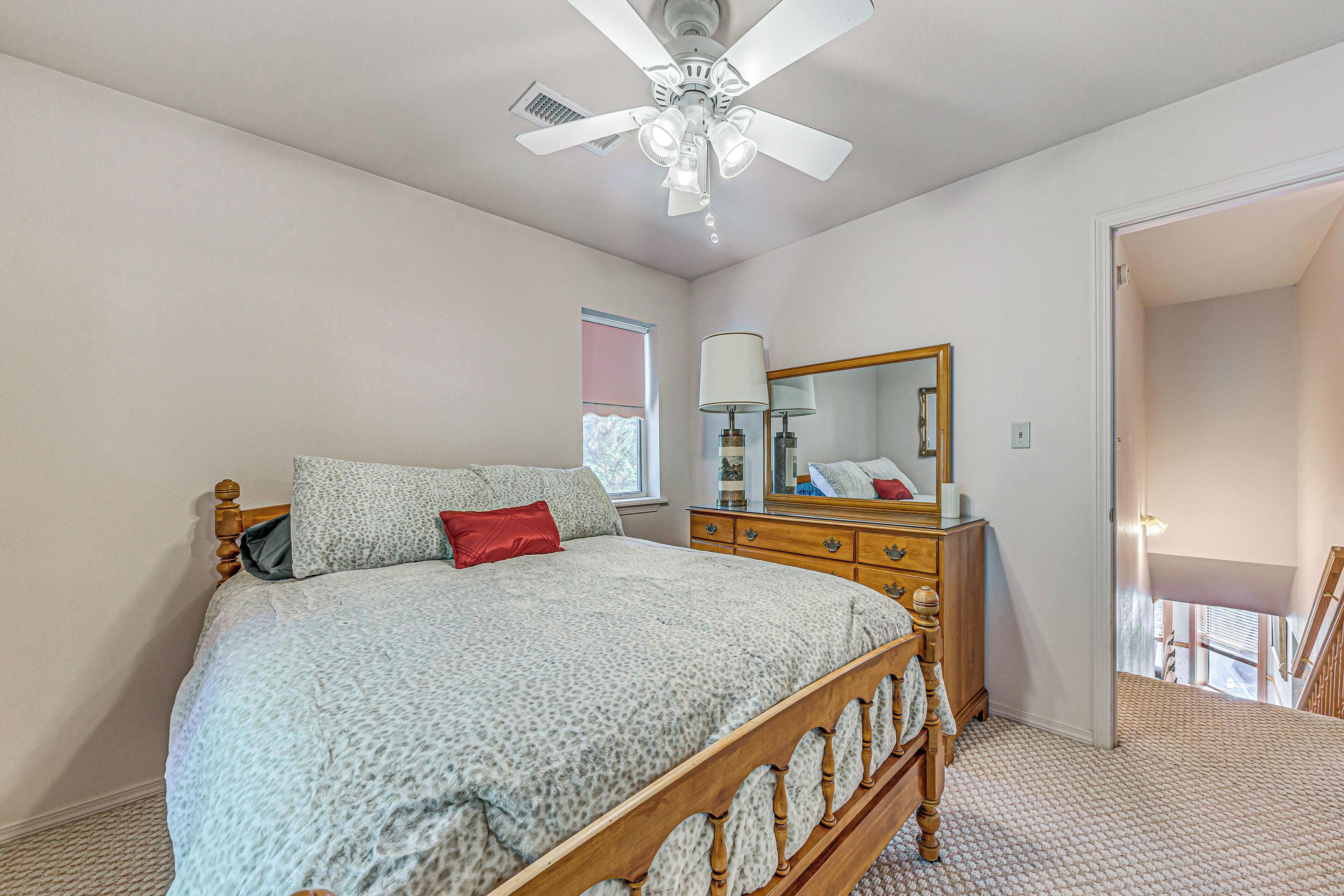 Une chambre à coucher avec un lit, une commode, un miroir et un ventilateur de plafond.