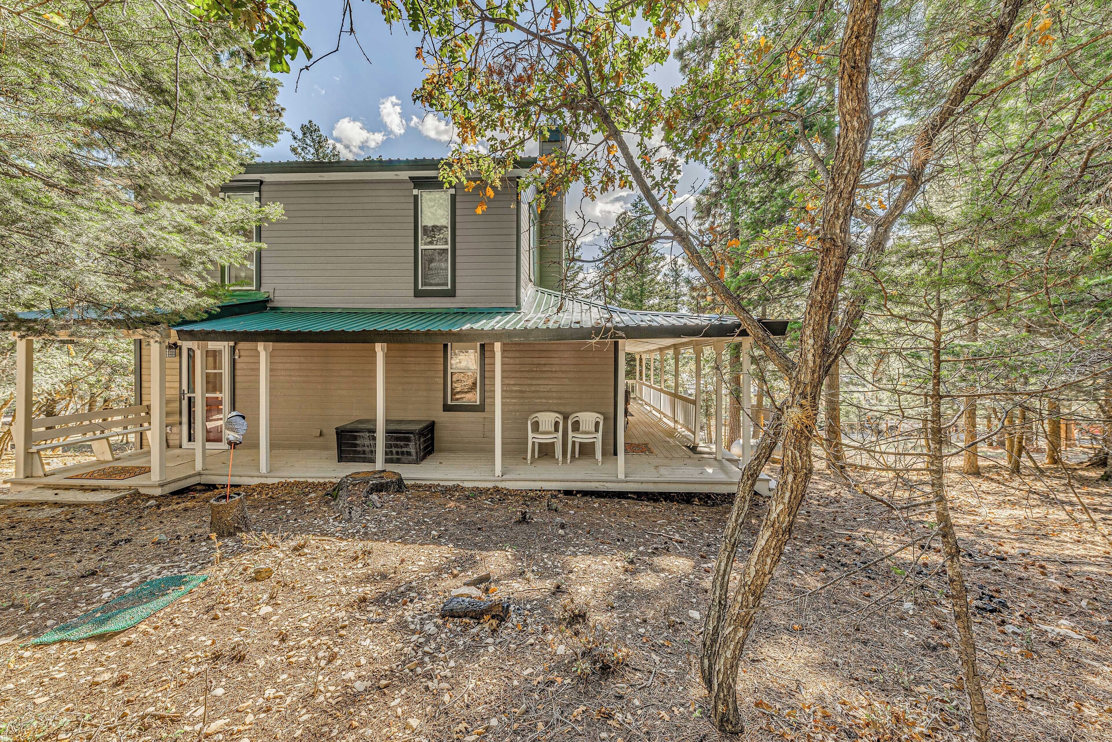 A two-story cabin with a covered porch and a small deck area.