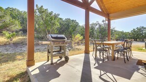 Une terrasse extérieure équipée d’un barbecue, de tables et de chaises.