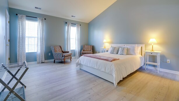 A bedroom with a large bed, two nightstands, a chair, and a window with curtains. - Group Getaway ~ 15 Mi to Charlottesville! (Troy)