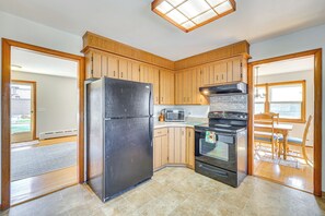 Una cocina con armarios de madera, un refrigerador negro, un microondas y una estufa.