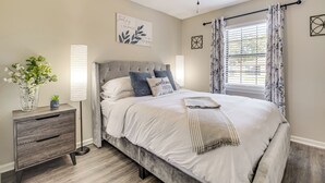 Un dormitorio con cama, mesita de noche, lámpara y ventilador de techo.