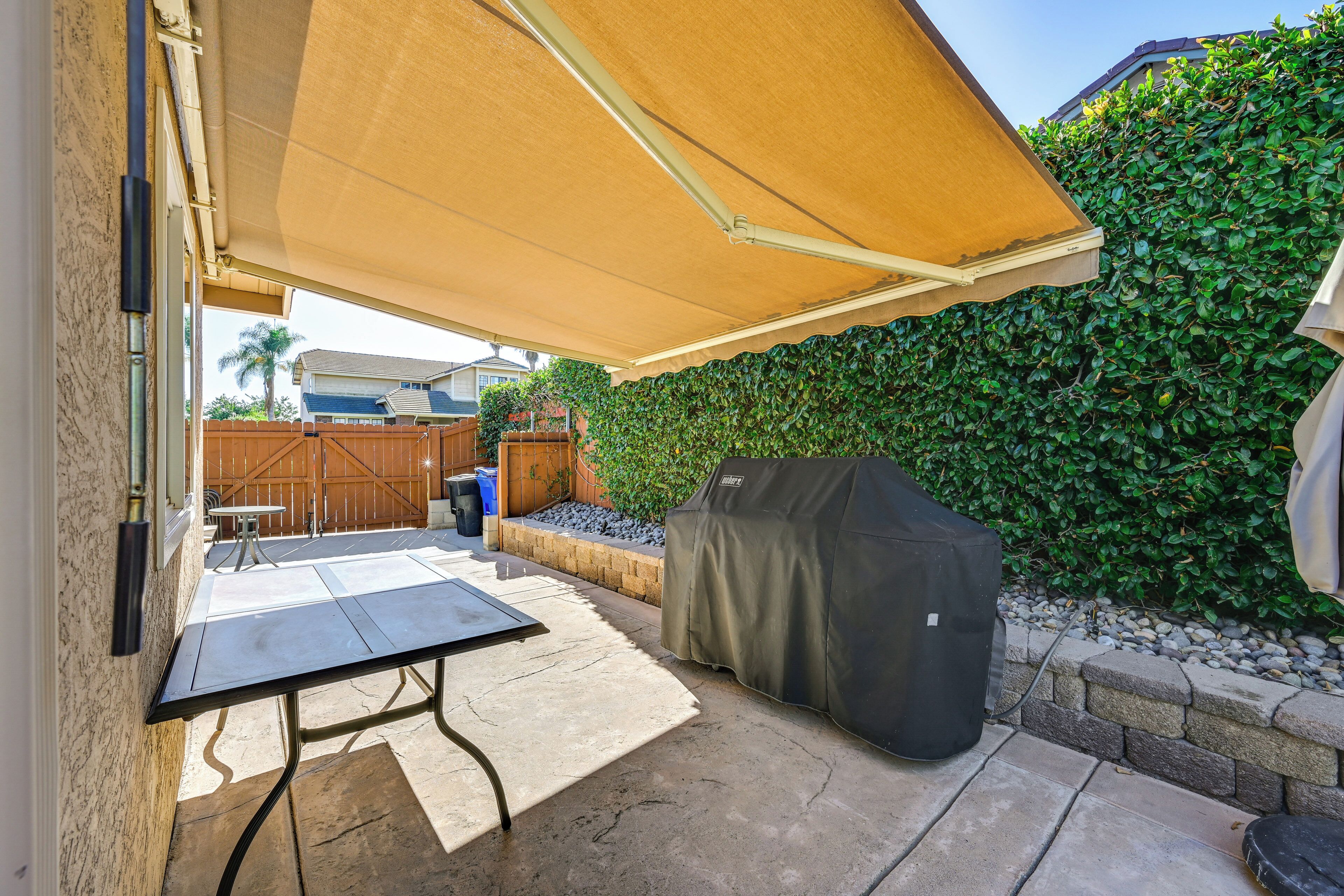 An outdoor patio with a table and chairs, a barbecue grill, and a covered seating area.