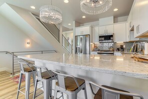 A modern kitchen with a large island, stainless steel appliances, and a staircase. - < 2 Mi to Dtwn Reno: Luxe Midtown Gem w/ Patio (Reno)