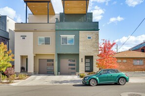 A modern two-story residential building with a garage, a green car parked in front, and a tree with red leaves to the right. - < 2 Mi to Dtwn Reno: Luxe Midtown Gem w/ Patio (Reno)
