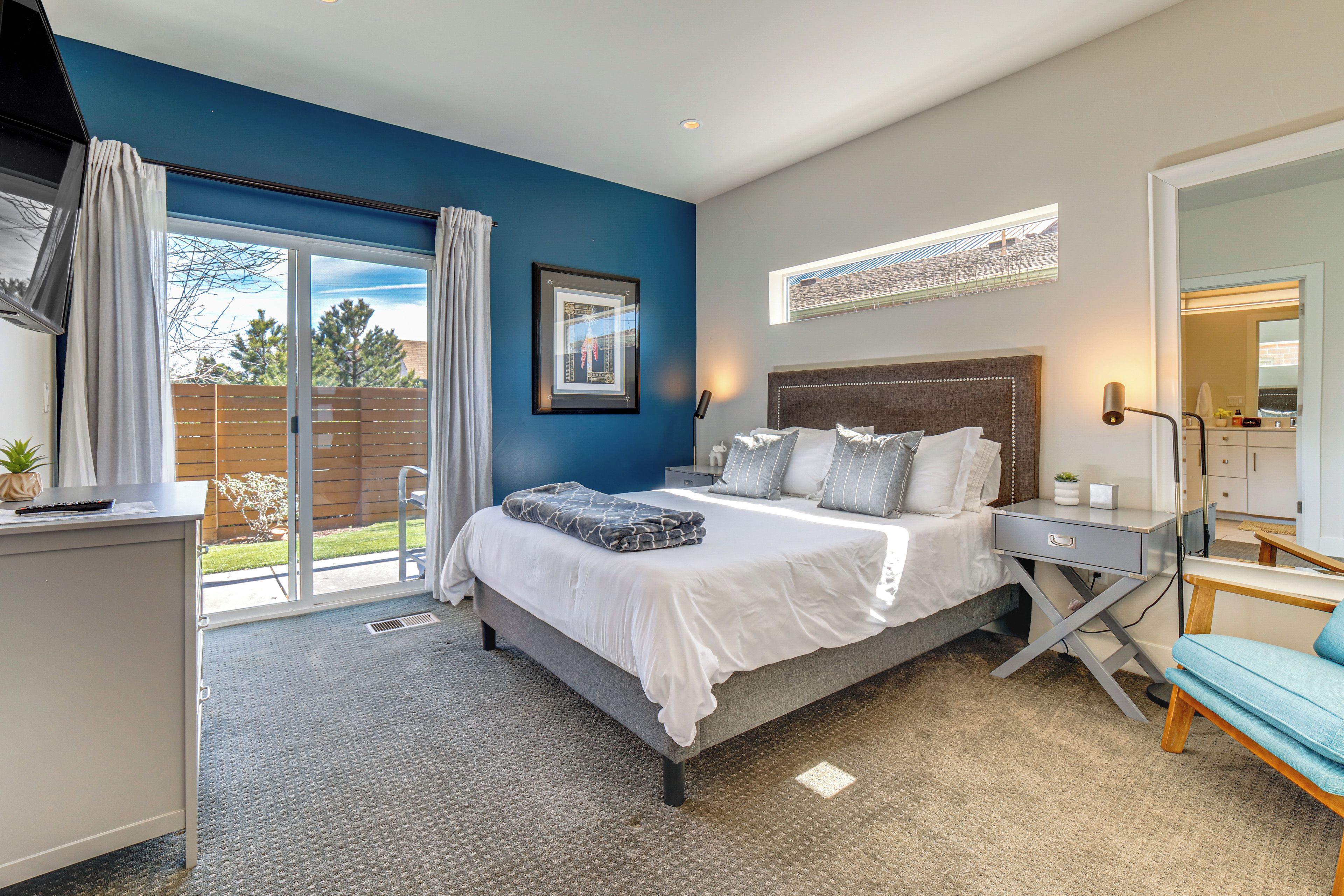 A modern bedroom with a large bed, a desk, and a chair.