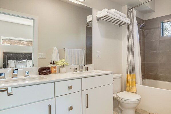 A modern bathroom with a large mirror, a white sink, a toilet, and a bathtub. - < 2 Mi to Dtwn Reno: Luxe Midtown Gem w/ Patio (Reno)