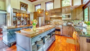 A spacious kitchen with wooden cabinets, a large island with a sink, and a stone fireplace. - Golf Getaway w/ Hot Tub, Course Views in Cle Elum! (Cle Elum)