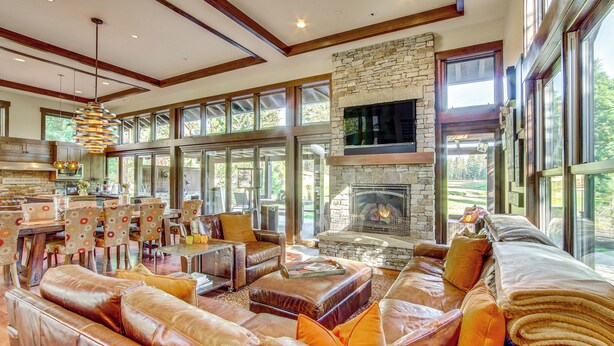 A spacious living area with leather sofas, a stone fireplace, and large windows offering views of the outdoors. - Golf Getaway w/ Hot Tub, Course Views in Cle Elum! (Cle Elum)