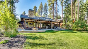A modern lodge with a stone facade, wooden deck, and outdoor seating area surrounded by tall pine trees. - Golf Getaway w/ Hot Tub, Course Views in Cle Elum! (Cle Elum)
