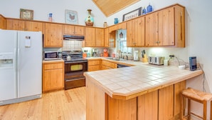 Una cucina con mobili in legno, un frigorifero, un forno a microonde, un forno e una macchina per il caffè.