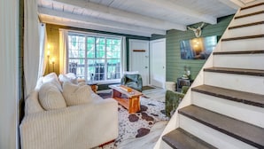 Ein gemütliches Wohnzimmer mit einer Holztreppe, einem großen Fenster und einem Cowhide-Teppich.