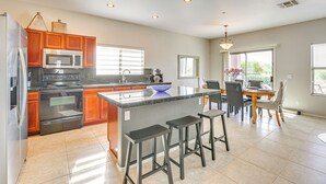 Una cocina moderna con una isla central, electrodomésticos de acero inoxidable y un comedor con mesa y sillas.