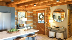 A kitchen with a marble countertop, wooden cabinets, and a large mirror. There are stools and a small table with a lamp. - 3 Mi to Dtwn: Mtn-view Cabin in Gatlinburg! (Gatlinburg)