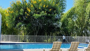 Une piscine avec des chaises longues et une clôture blanche.
